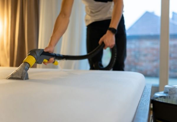 Mattress cleaning process. Man cleans bed from dirt and bacteria